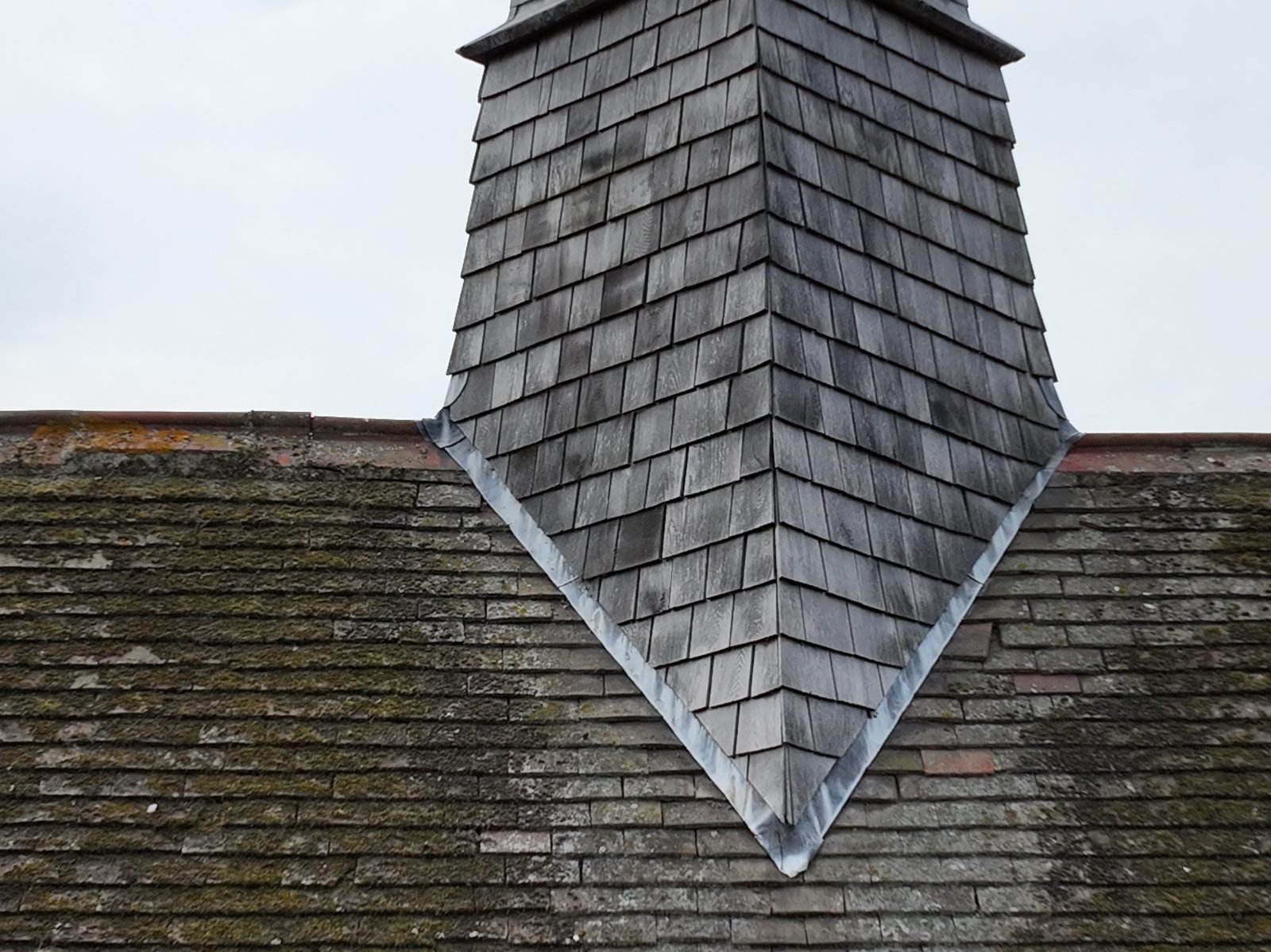Drone photograph of the diagonally set bell turret and timber spirelet at St John the Evangelist, March, above cement-tiled roof slopes