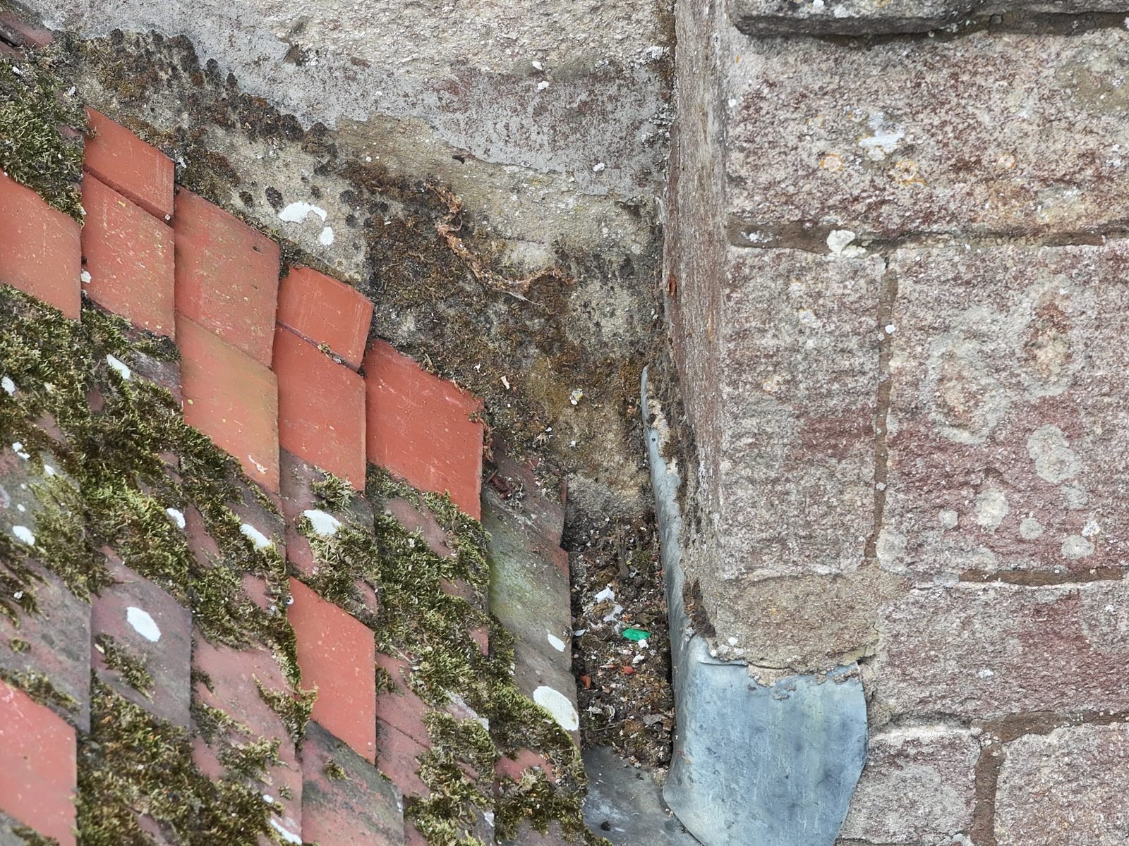 Detail drone photograph along the roof-to-tower abutment at St Thomas à Becket church, Ramsey, showing replacement tiles and the mortar fillet